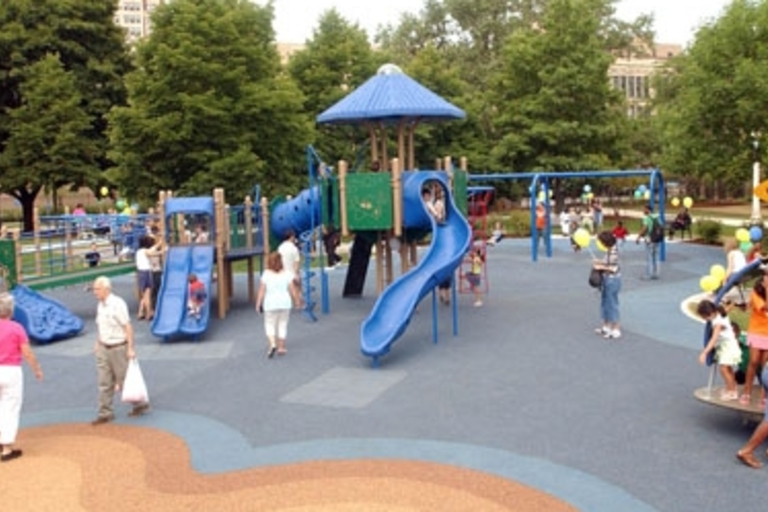 Busy playground with children and adults on a sunny day.
