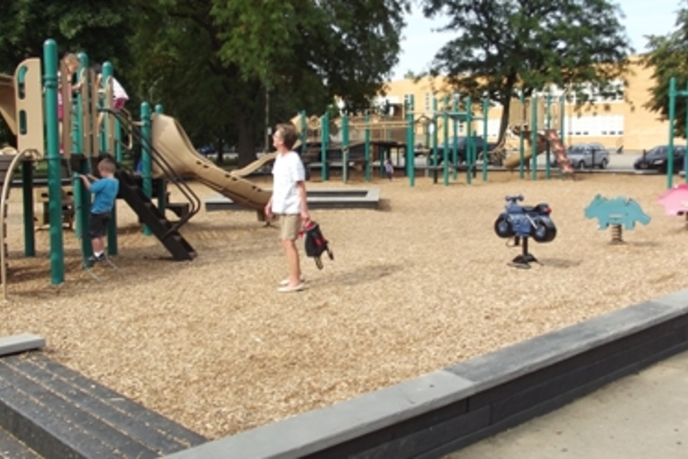Children play on a playground with woodchip ground cover.