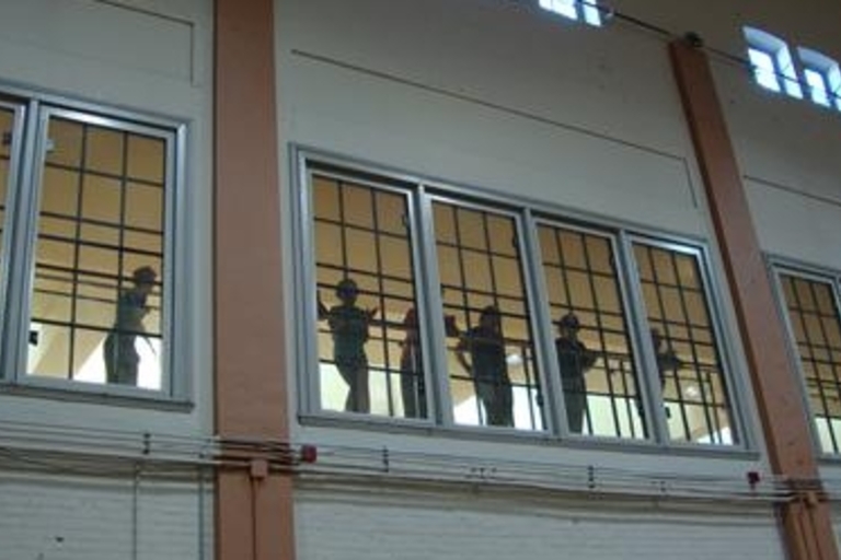 Silhouetted figures in upper story windows of a large room.