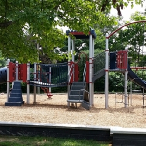 Red, white, and blue playground equipment on wood chips.