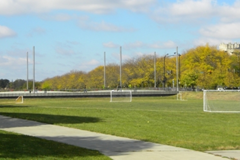 Soccer field with goals, paved walking path, and autumn trees.