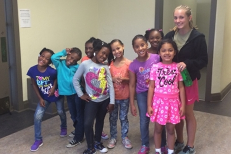 Group photo of a teenage girl and elementary school girls in a hallway.
