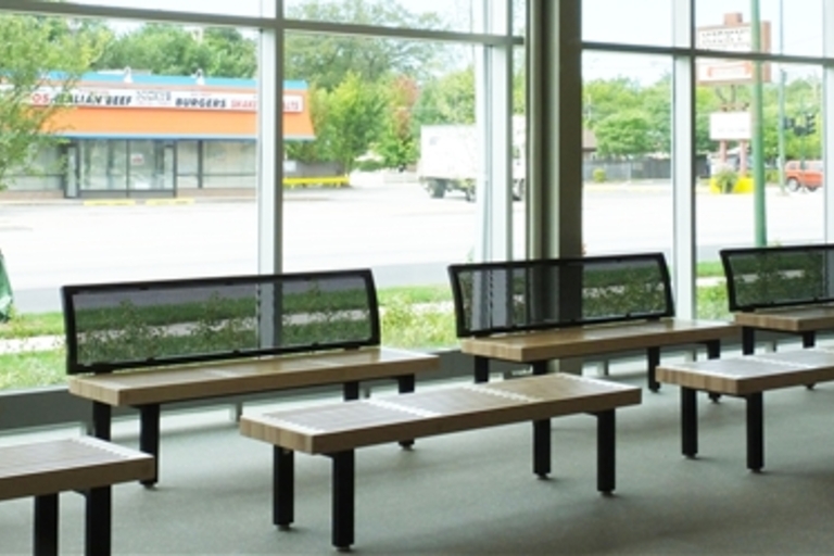 Modern waiting area with wood and metal benches by large windows.