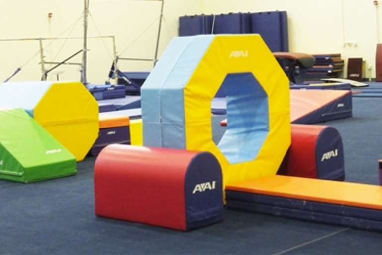 Colorful padded gymnastics equipment in a gym.