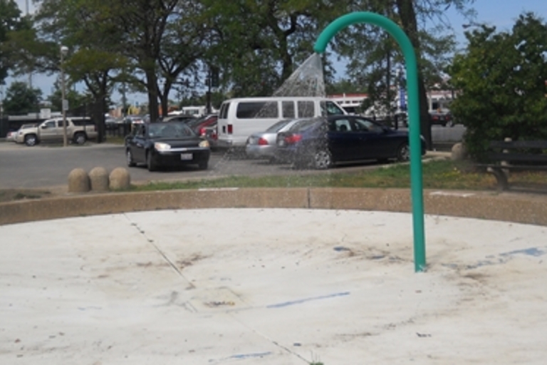 Green splash pad sprinkler spraying water.
