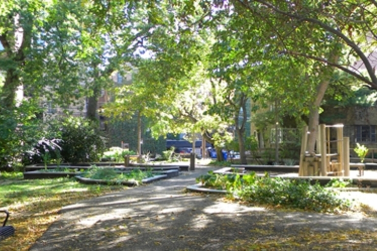 Shady neighborhood park with playground, benches, and community garden.