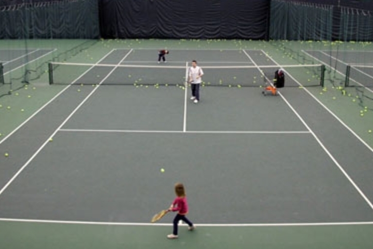 Family playing tennis on an indoor court.