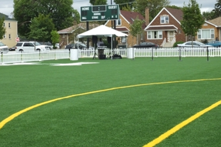 Green turf field with yellow lines and a scoreboard.