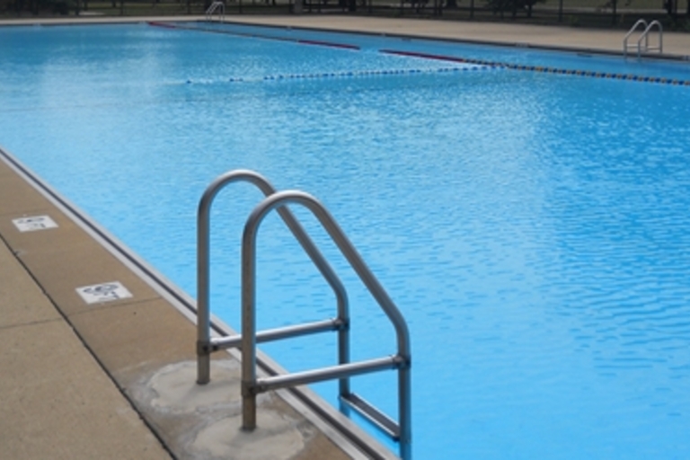 Inviting blue swimming pool with metal handrails.
