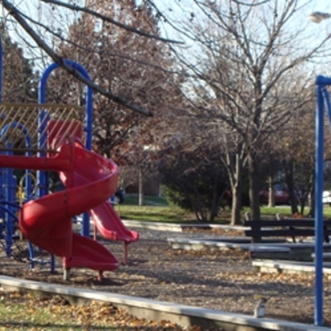 Playground with red slide, blue climbing frame, and swings.
