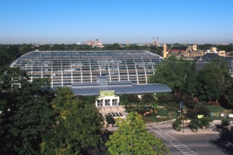The Garfield Park Conservatory surrounded by trees and other buildings on a sunny day.