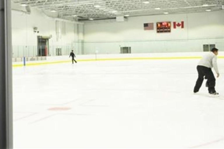 Indoor ice rink with several skaters.