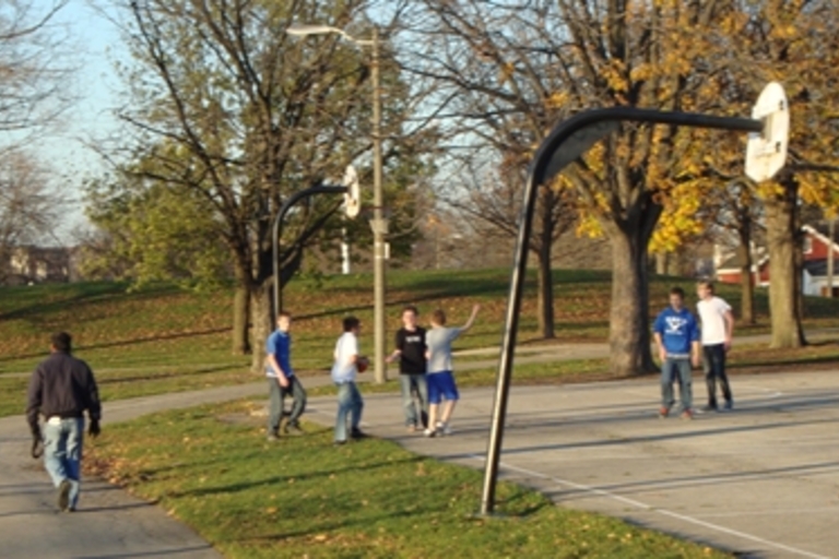 Teens play basketball in a park on an autumn afternoon.