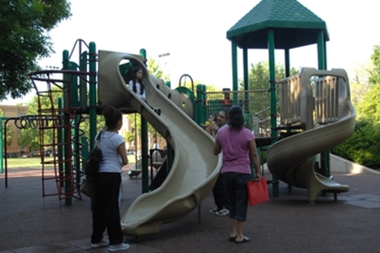 Children and adults play on a playground slide.

