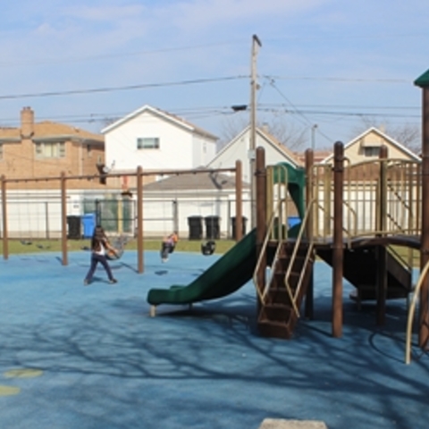 Children playing on playground equipment with blue rubberized ground.