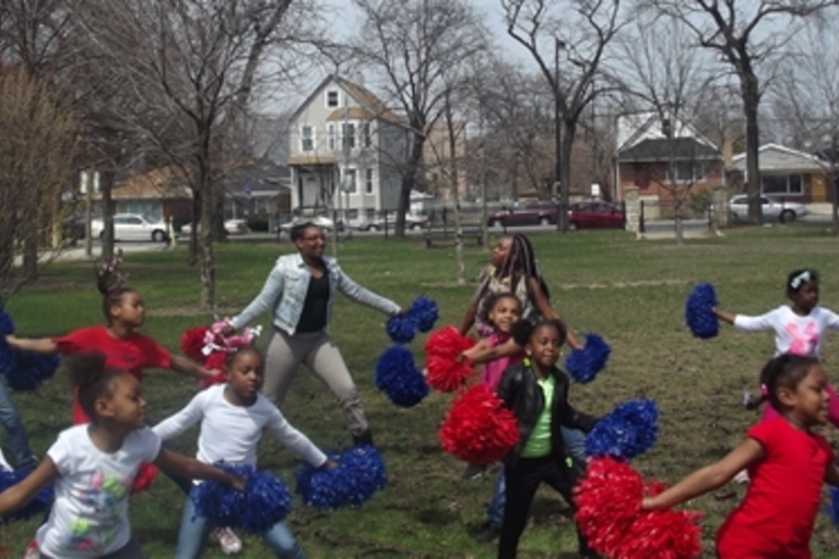 Cheerleaders practice in a park.
