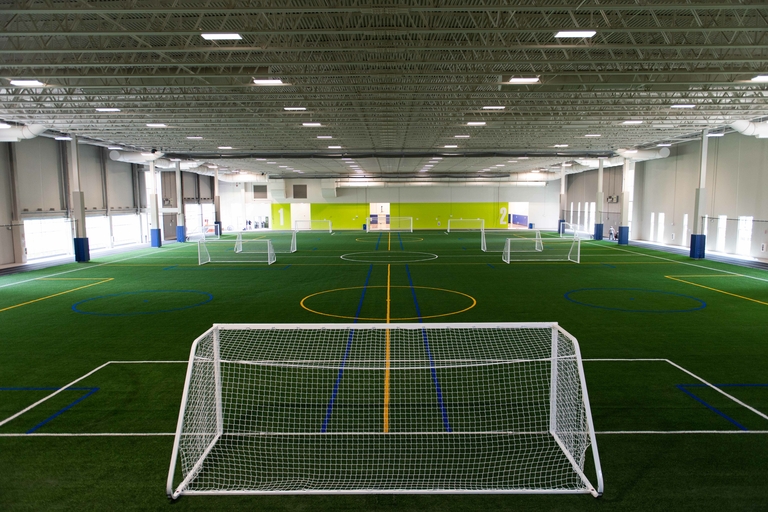 Indoor soccer field with white and blue lines and several goals.