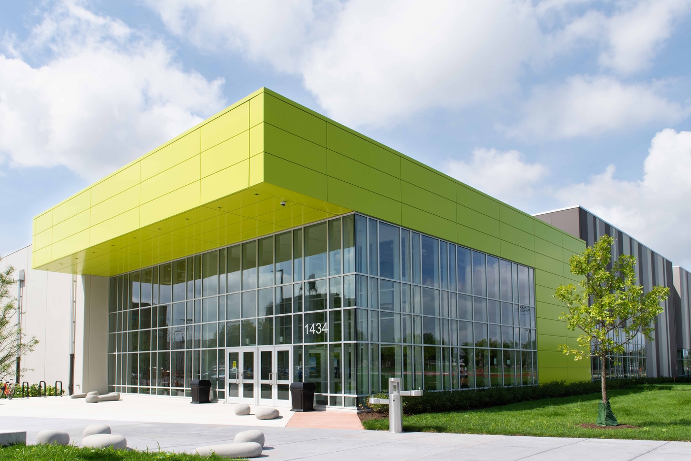 Modern building with large green panels and glass facade.