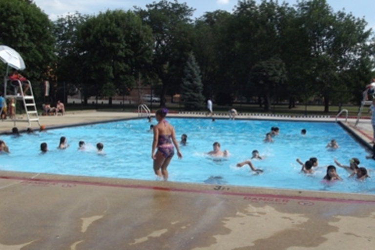 Children swimming in a public pool on a sunny day.