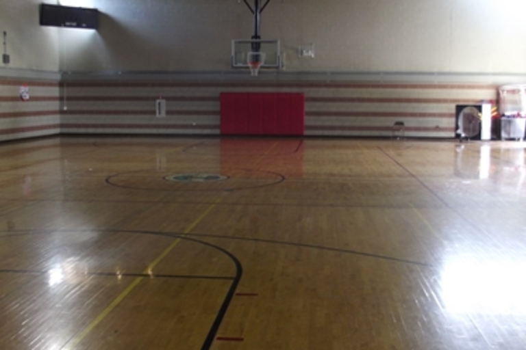 Empty high school gymnasium with polished wooden floor.
