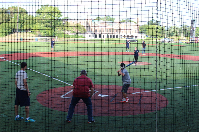 A batter up at bat behind a net at a baseball game.