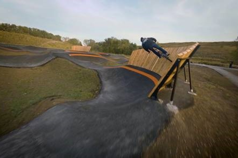 BMX rider going airborne on a pump track.