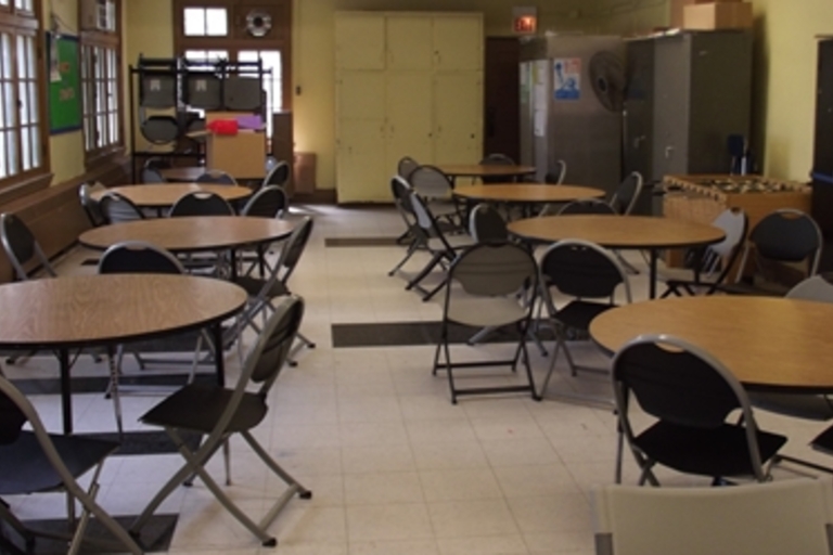 Empty community room with round tables and folding chairs.
