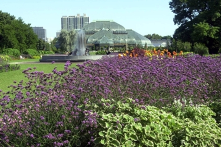 Flower gardens, a fountain, and a conservatory in a city park.