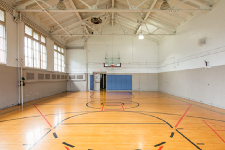 Empty indoor basketball court with light wood floor.