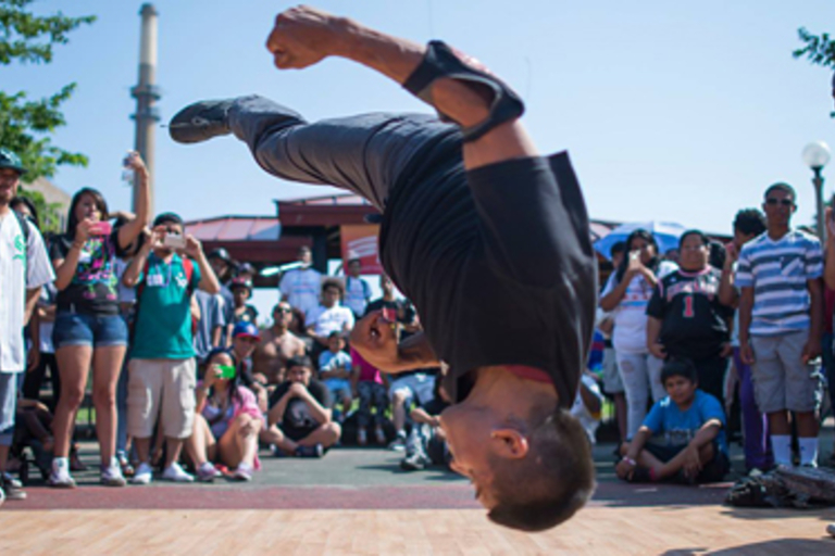Breakdancer flips upside down in front of a crowd.
