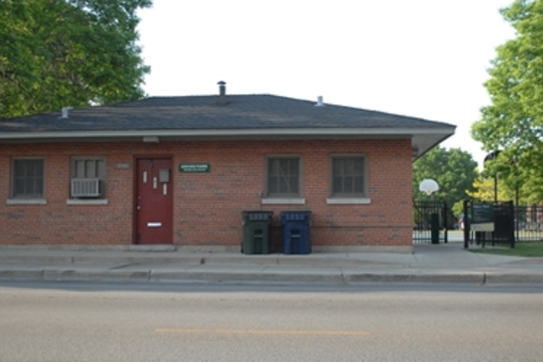 Small brick park building with a red door.