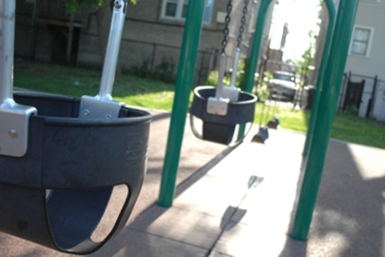 Empty baby swings on a playground.
