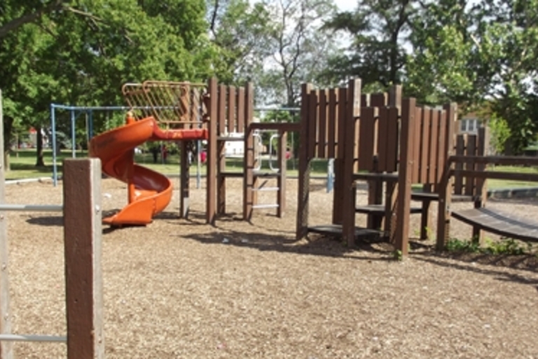 Playground with wooden climbing frame and orange slide.

