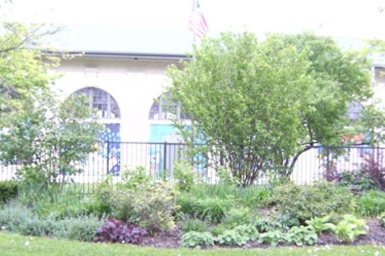 Community garden in front of building with arched windows.