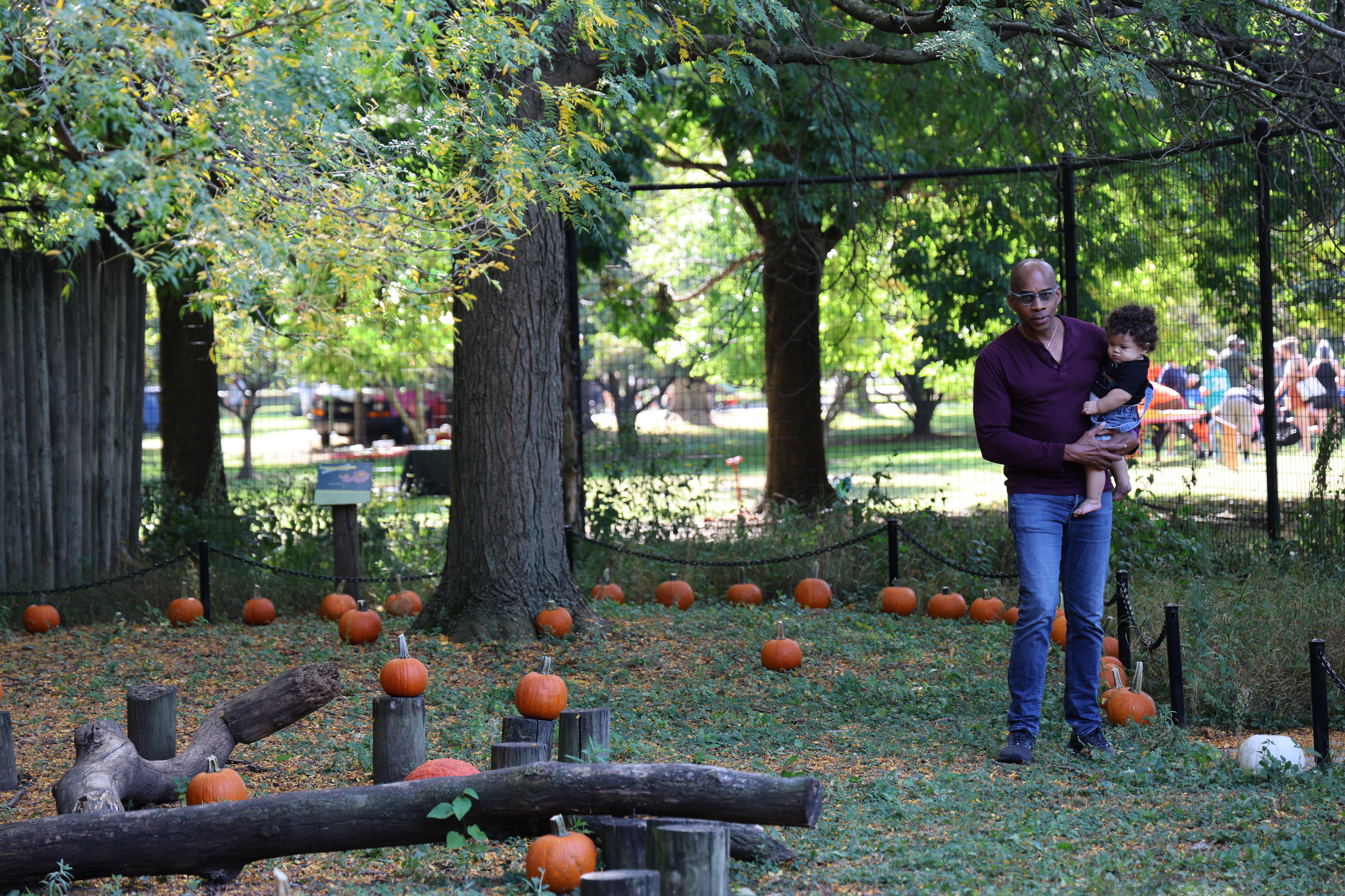 Photograph of man holding toddler in pumpkin patch.
