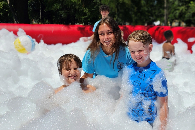 Two children and a teen play in a foam pit.