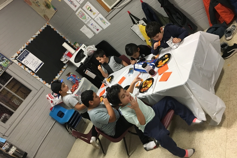 Children eating snacks at a table in a classroom.