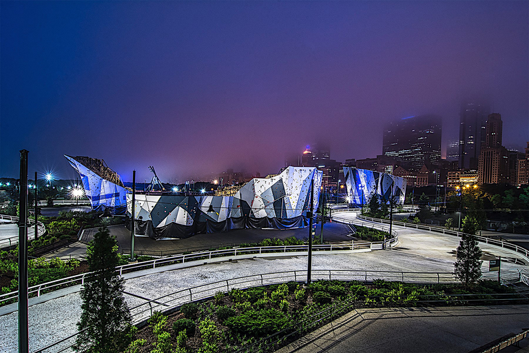 Climbing wall at night with a misty city skyline in the background.