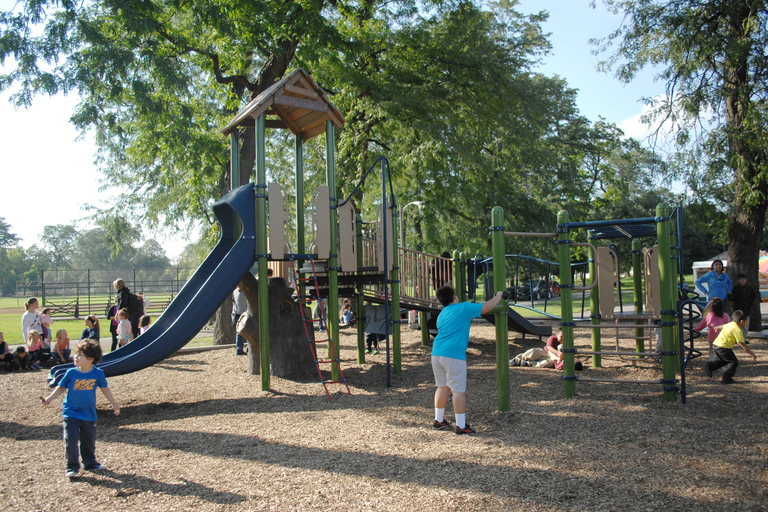 Children play on a playground with slides and climbing structures.