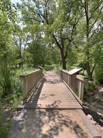 Wooden footbridge over a small creek in a wooded park.