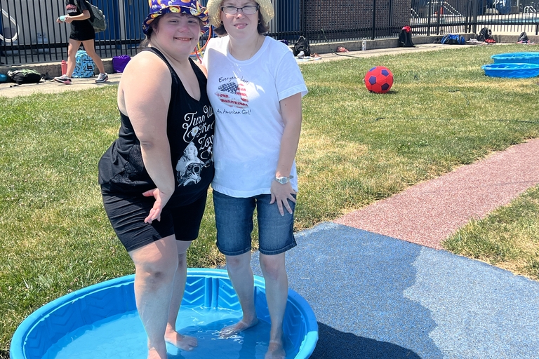 Two people cool their feet in a small wading pool on a sunny day.