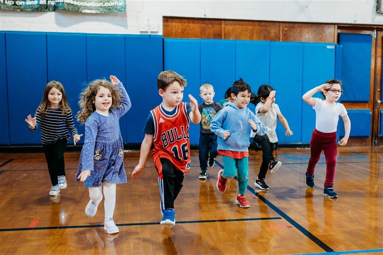 Children run across a gymnasium floor.
