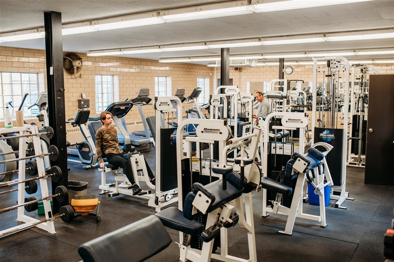 Gym with weight machines and a person using an exercise bike.
