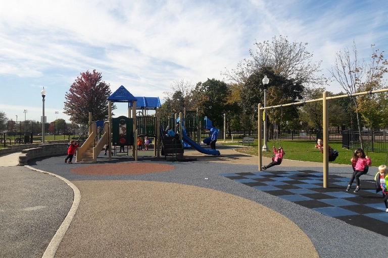 Children play on swings and playground equipment at a park.