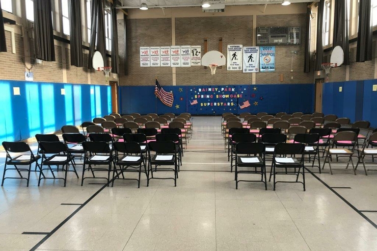 School gymnasium set up with rows of chairs for an event.