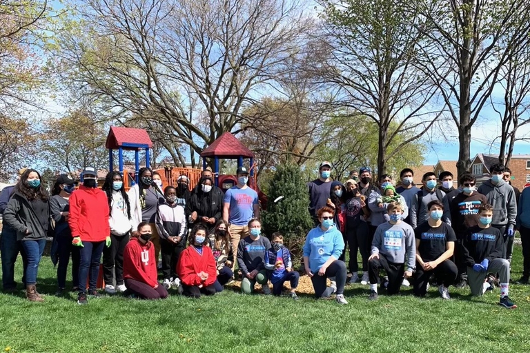 Group photo of volunteers in matching blue t-shirts at a park cleanup.