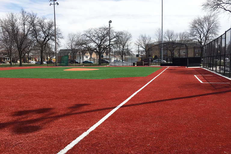 Empty baseball field with red turf infield and green turf outfield.