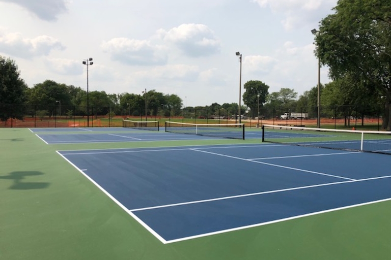 Empty blue and green tennis courts on a sunny day.