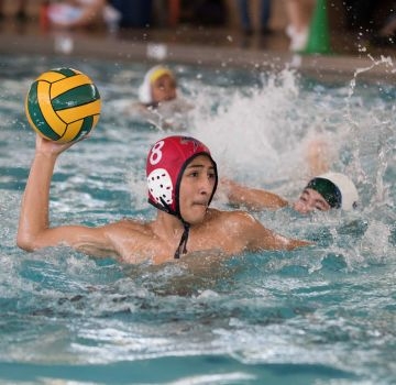 Water polo player prepares to throw the ball in a pool with another player approaching.