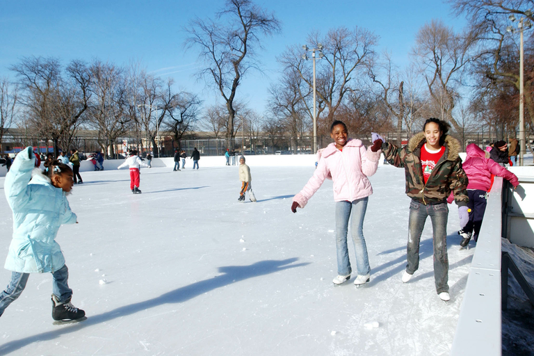 Children ice skating outdoors on a sunny winter day.
